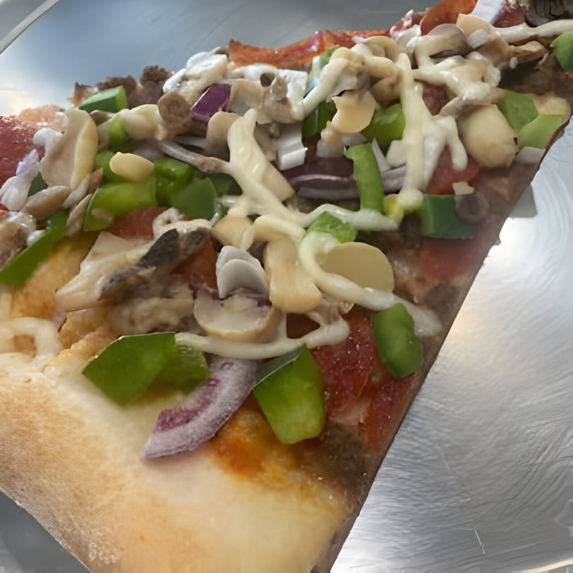 Close-up of a Jonuzi Southside Pizza slice with pepperoni, mushrooms, green peppers, and onions.